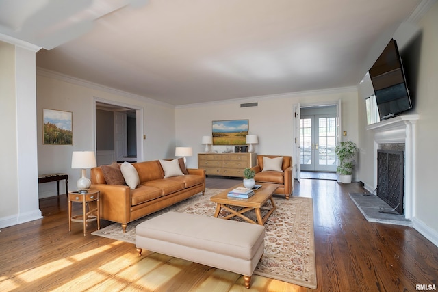 living area featuring ornamental molding, visible vents, baseboards, and wood finished floors