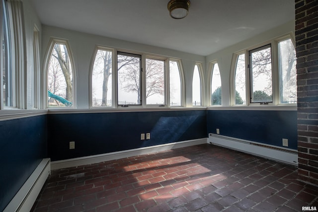 unfurnished sunroom with a baseboard radiator, a wealth of natural light, and brick floor