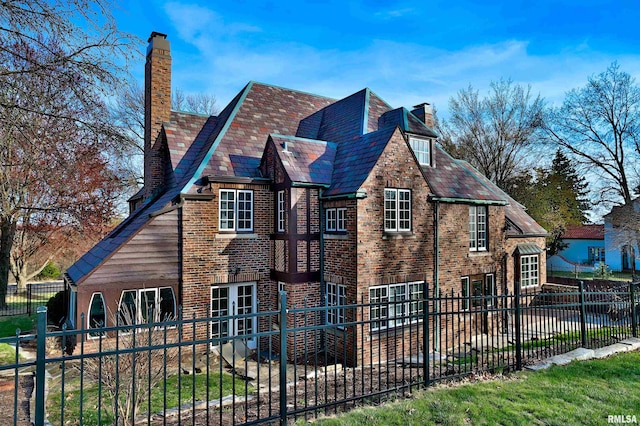 view of home's exterior with a high end roof, a chimney, a fenced backyard, and brick siding