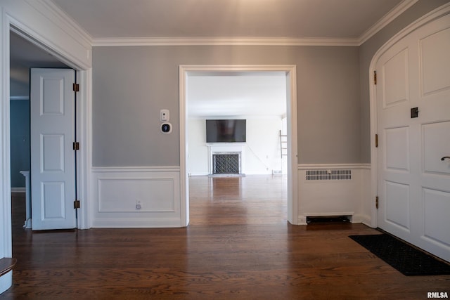 entryway with a decorative wall, ornamental molding, a wainscoted wall, and wood finished floors