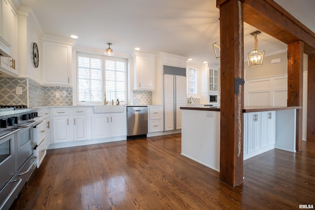 kitchen featuring dark wood finished floors, appliances with stainless steel finishes, a sink, and white cabinetry