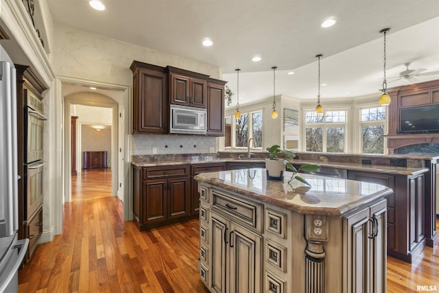 1801 Kern Rd, Washington, IL 61571 - kitchen featuring white microwave, a center island, a peninsula, a sink, and wood finished floors