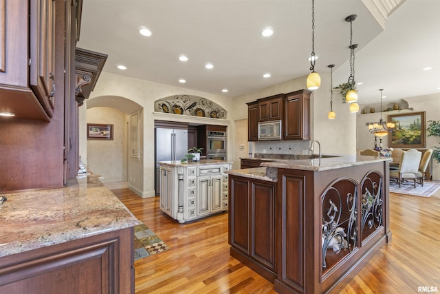 1801 Kern Rd, Washington, IL 61571 - kitchen with appliances with stainless steel finishes, arched walkways, light wood finished floors, light stone counters, and recessed lighting