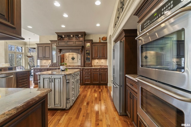 1801 Kern Rd, Washington, IL 61571 - kitchen featuring stainless steel appliances, light wood-style floors, tasteful backsplash, light stone counters, and hanging light fixtures