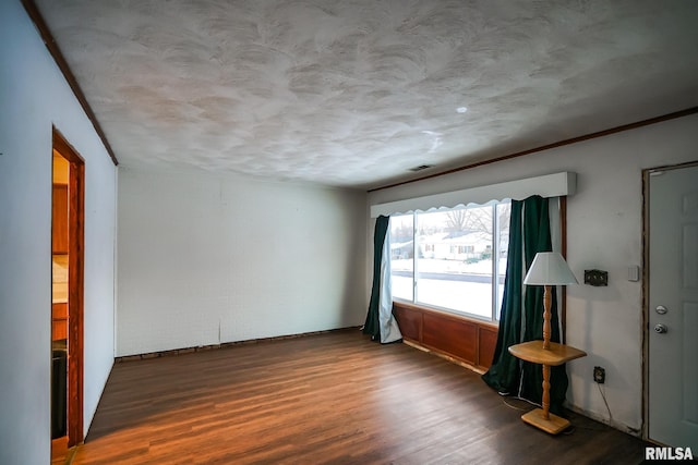 unfurnished room with a textured ceiling, wood finished floors, and visible vents