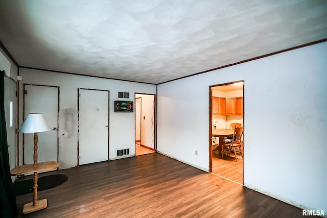 interior space with wood finished floors, visible vents, and ornamental molding