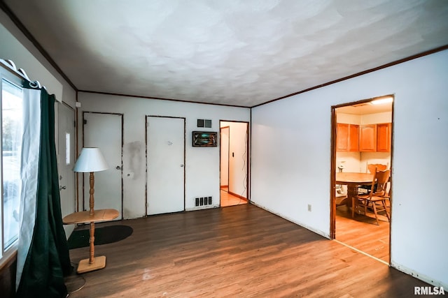 unfurnished bedroom with wood finished floors, visible vents, and crown molding