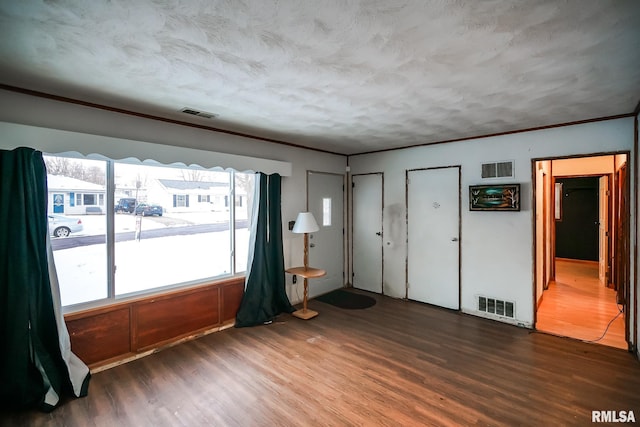 spare room with crown molding, wood finished floors, and visible vents