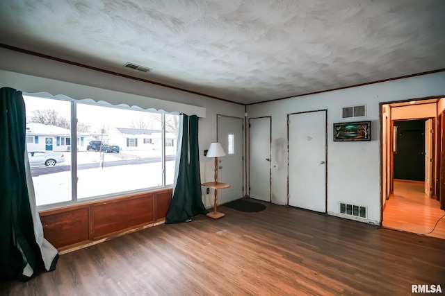 spare room with wood finished floors, visible vents, and ornamental molding