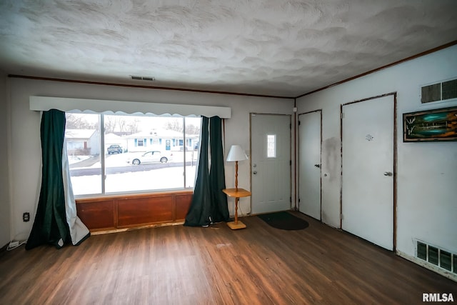 entrance foyer with visible vents, wood finished floors, and ornamental molding