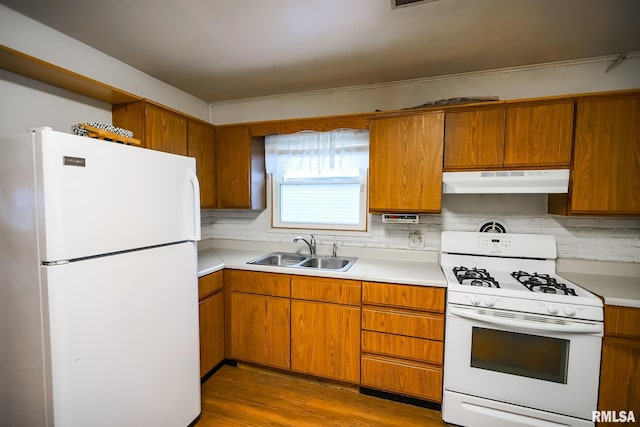 kitchen with a sink, white appliances, under cabinet range hood, brown cabinetry, and backsplash