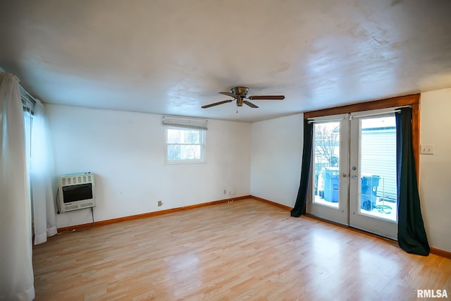 unfurnished room featuring heating unit, light wood-type flooring, ceiling fan, french doors, and baseboards