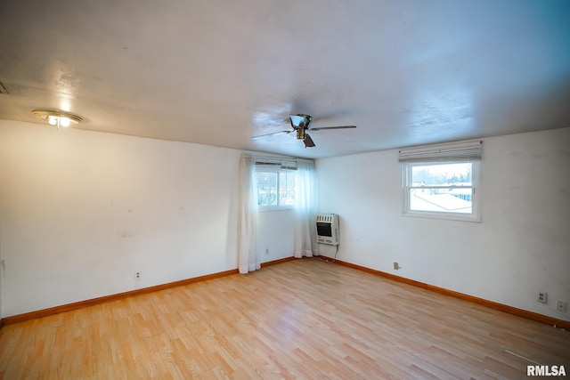 unfurnished room with light wood finished floors, heating unit, baseboards, and a ceiling fan