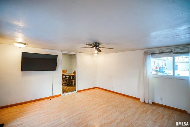 spare room featuring baseboards, light wood finished floors, and a ceiling fan