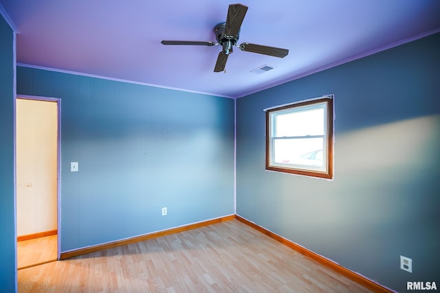 empty room featuring wood finished floors, ceiling fan, baseboards, ornamental molding, and visible vents