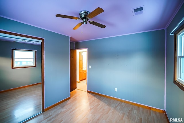 unfurnished bedroom with light wood-type flooring, ceiling fan, baseboards, ornamental molding, and visible vents