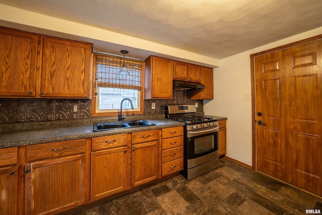 kitchen with stainless steel range with gas stovetop, under cabinet range hood, a sink, dark countertops, and backsplash