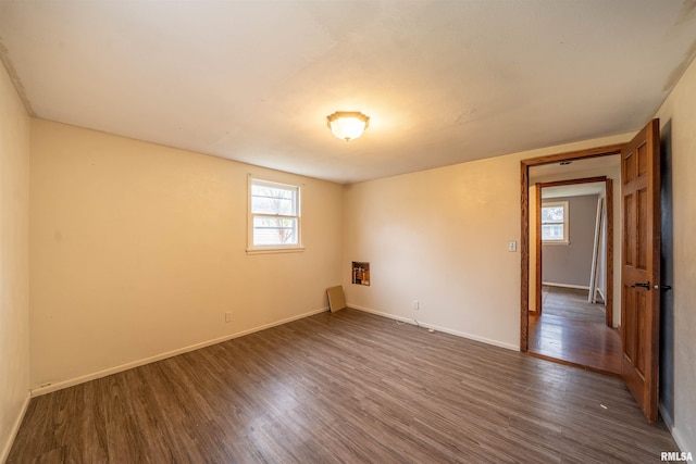 spare room with dark wood-style flooring and baseboards