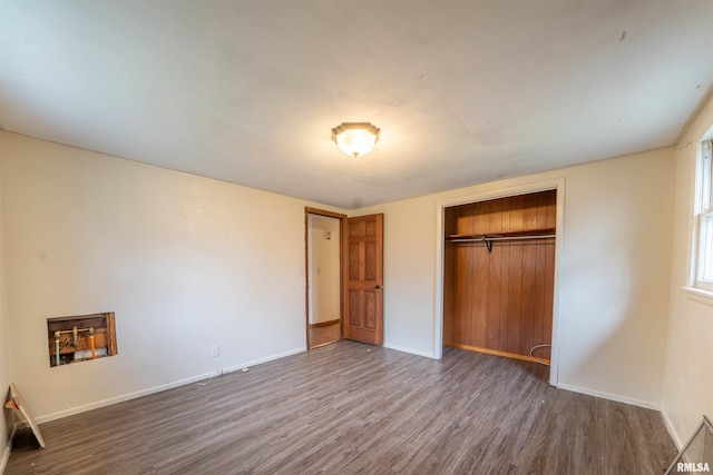 unfurnished bedroom with wood finished floors, a closet, and baseboards