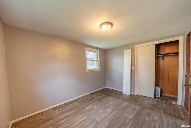 unfurnished bedroom with dark wood-style floors, a closet, and baseboards