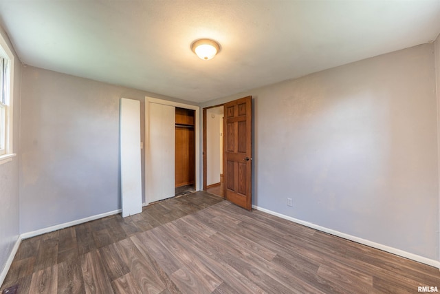 unfurnished bedroom with dark wood-style flooring and baseboards