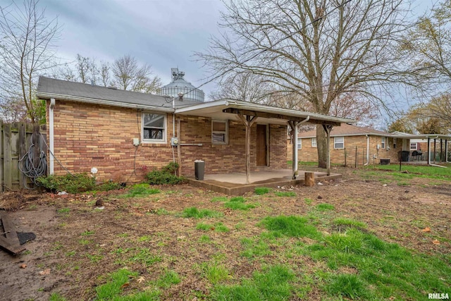 rear view of house featuring a patio area, fence, and brick siding