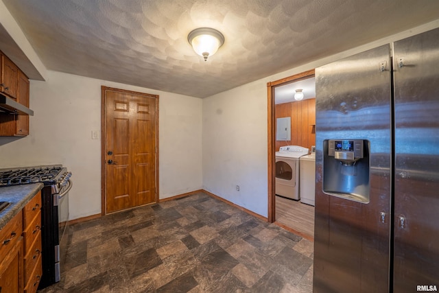 kitchen featuring baseboards, electric panel, washing machine and dryer, under cabinet range hood, and appliances with stainless steel finishes