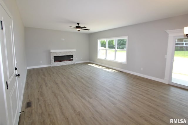 106 Samuel Ct, Washington, IL 61571 - unfurnished living room with ceiling fan, wood finished floors, a glass covered fireplace, and baseboards