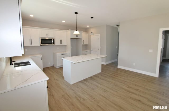 106 Samuel Ct, Washington, IL 61571 - kitchen with stainless steel microwave, a sink, light wood-style floors, a center island, and white cabinetry