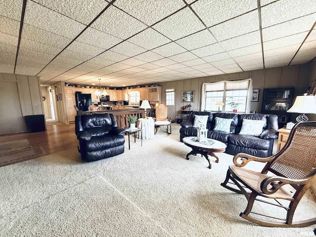 living room with a paneled ceiling and carpet flooring