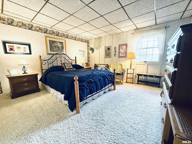 carpeted bedroom featuring a drop ceiling