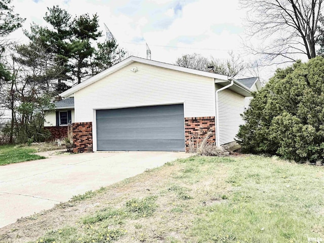 view of side of home featuring an attached garage, driveway, brick siding, and a yard