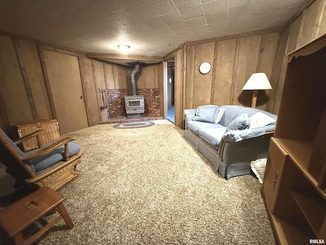 living room with wood walls, carpet floors, and a wood stove