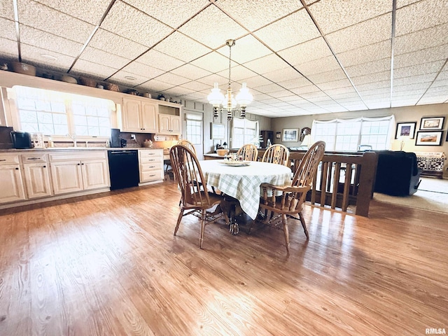 dining area with an inviting chandelier, light wood-type flooring, and a paneled ceiling