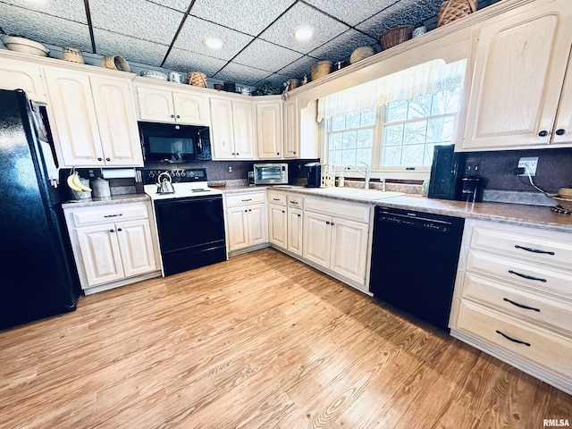 kitchen with light countertops, light wood-style floors, a sink, and black appliances