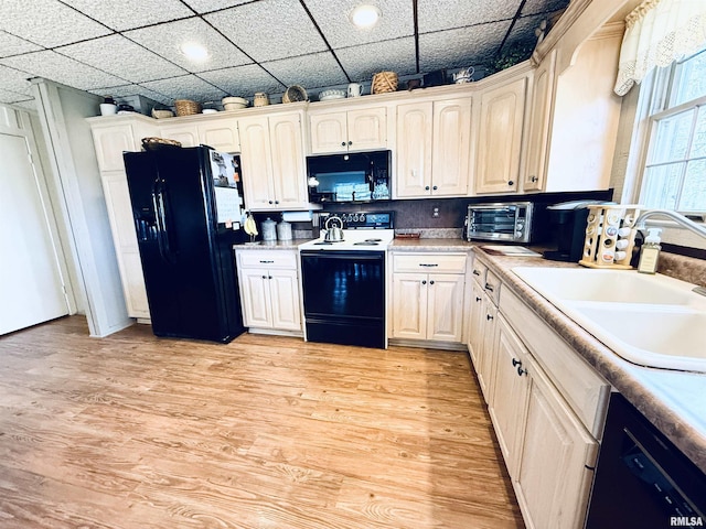 kitchen with a toaster, light countertops, a sink, light wood-type flooring, and black appliances