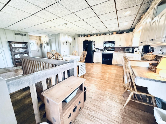 dining room with light wood-style floors, a paneled ceiling, visible vents, and a toaster