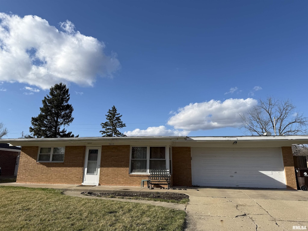 ranch-style house featuring brick siding, a front yard, driveway, and a garage