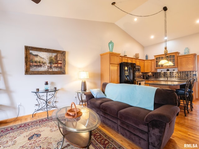 living area featuring high vaulted ceiling, light wood finished floors, and recessed lighting