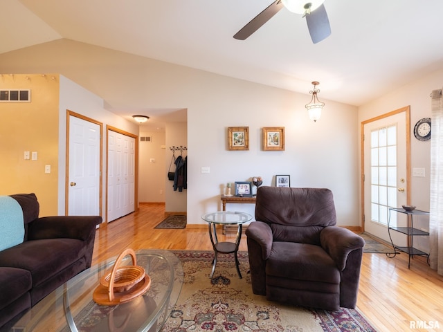 living area with baseboards, vaulted ceiling, visible vents, ceiling fan, and light wood finished floors