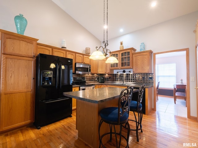 kitchen featuring tasteful backsplash, glass insert cabinets, a center island, stainless steel appliances, and a sink
