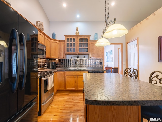 kitchen featuring a kitchen breakfast bar, light wood-style flooring, backsplash, stainless steel appliances, and a sink