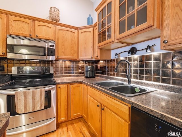 kitchen with tasteful backsplash, appliances with stainless steel finishes, a sink, and light wood-style floors