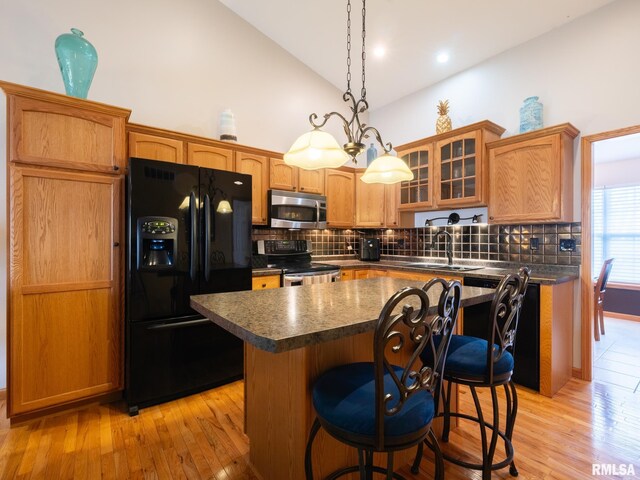 kitchen with black appliances, a kitchen island, dark countertops, a sink, and decorative backsplash