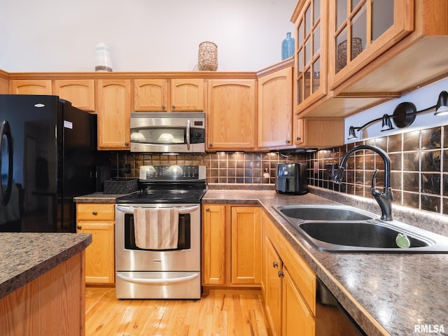kitchen with decorative backsplash, glass insert cabinets, a sink, and appliances with stainless steel finishes