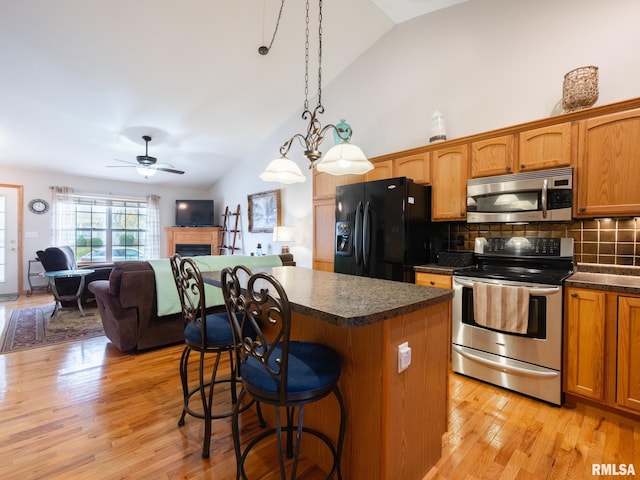 kitchen featuring tasteful backsplash, appliances with stainless steel finishes, dark countertops, and vaulted ceiling