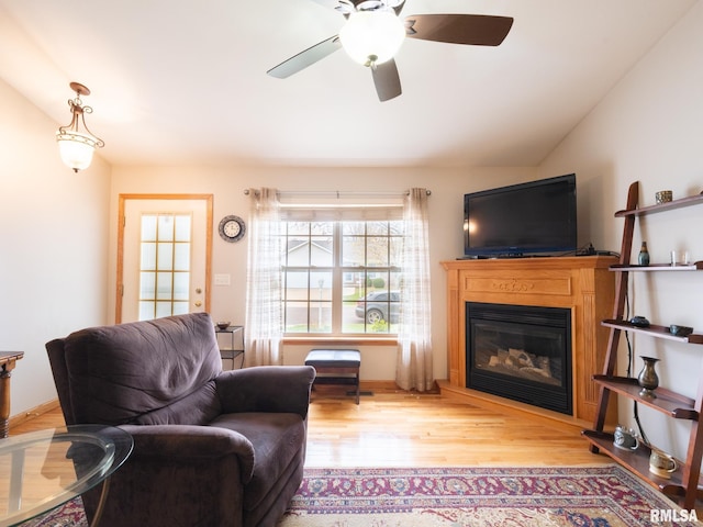 living room with a glass covered fireplace, lofted ceiling, ceiling fan, and wood finished floors