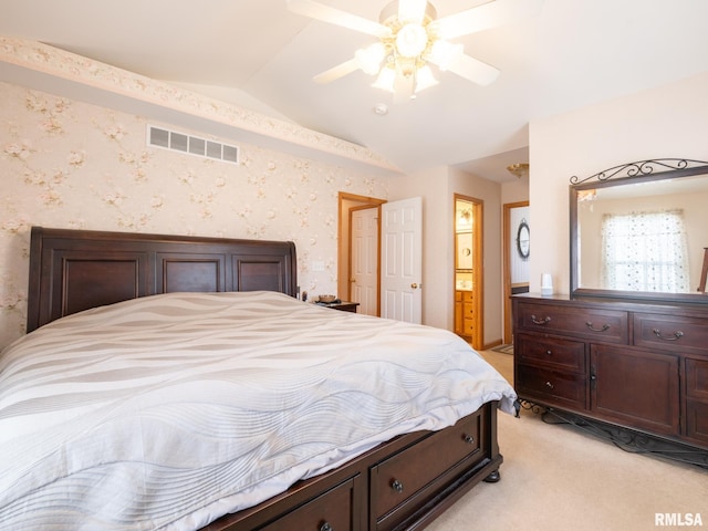 bedroom with vaulted ceiling, ensuite bath, a ceiling fan, visible vents, and light colored carpet