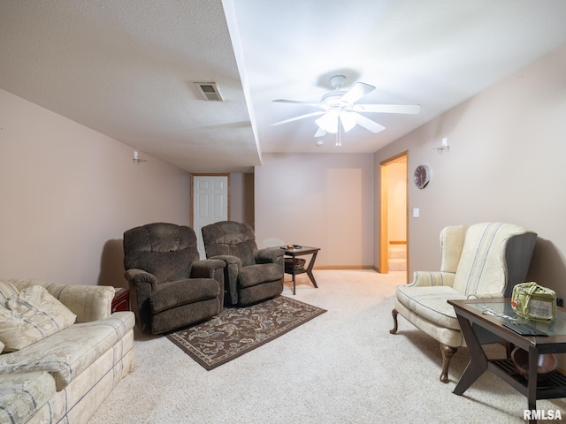 carpeted living area featuring visible vents and a ceiling fan