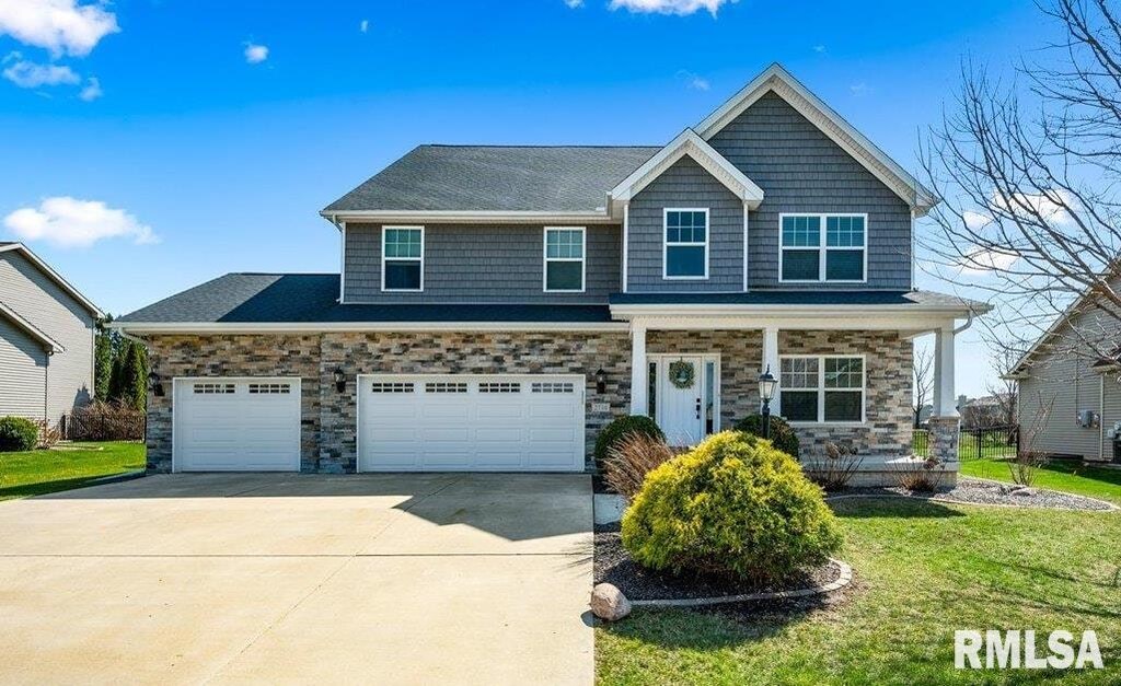 2710 W Quartz St, Dunlap, IL 61525 - view of front facade featuring driveway, a front yard, an attached garage, a porch, and stone siding
